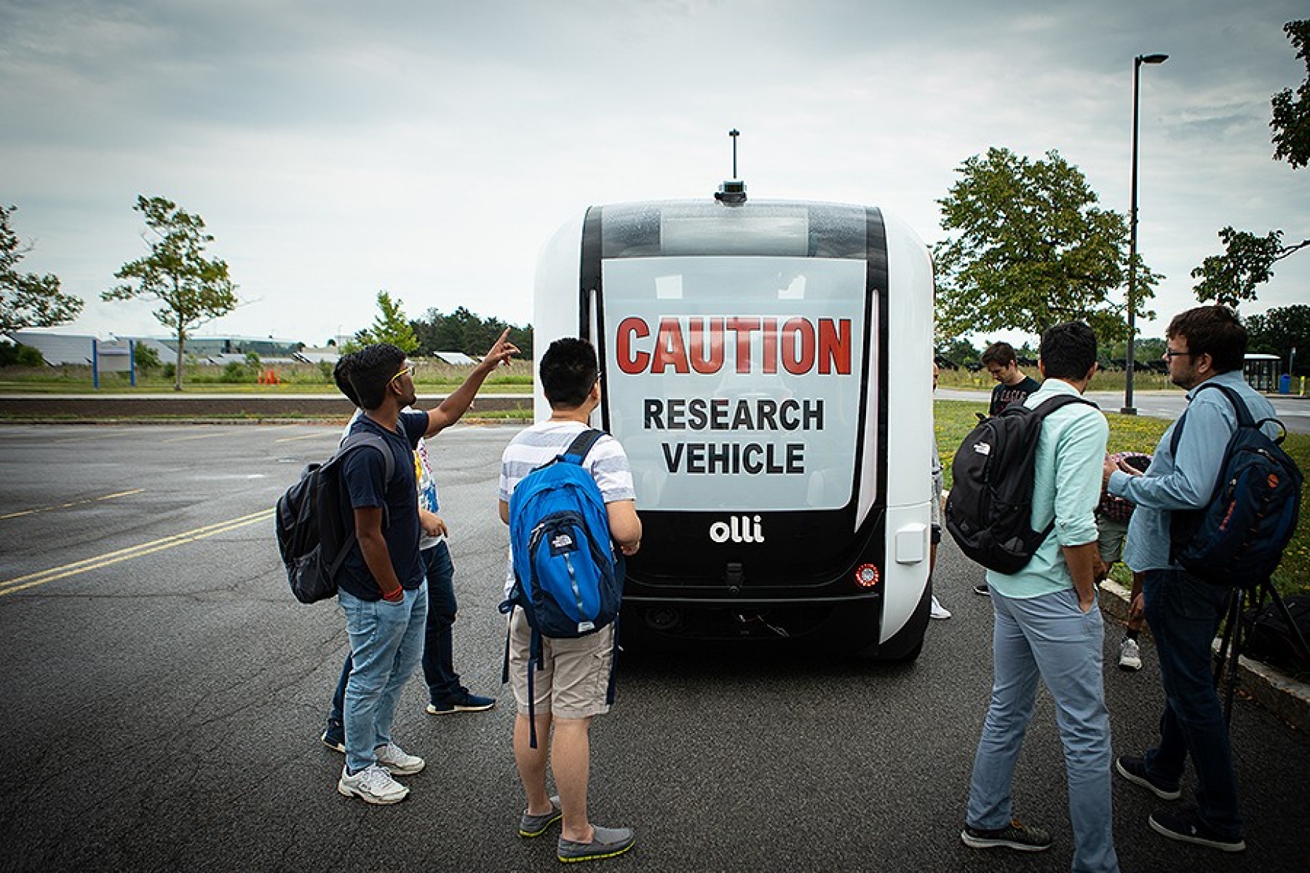 A UB student points to one of the sensors on Olli, the self-driving electric shuttle. 
