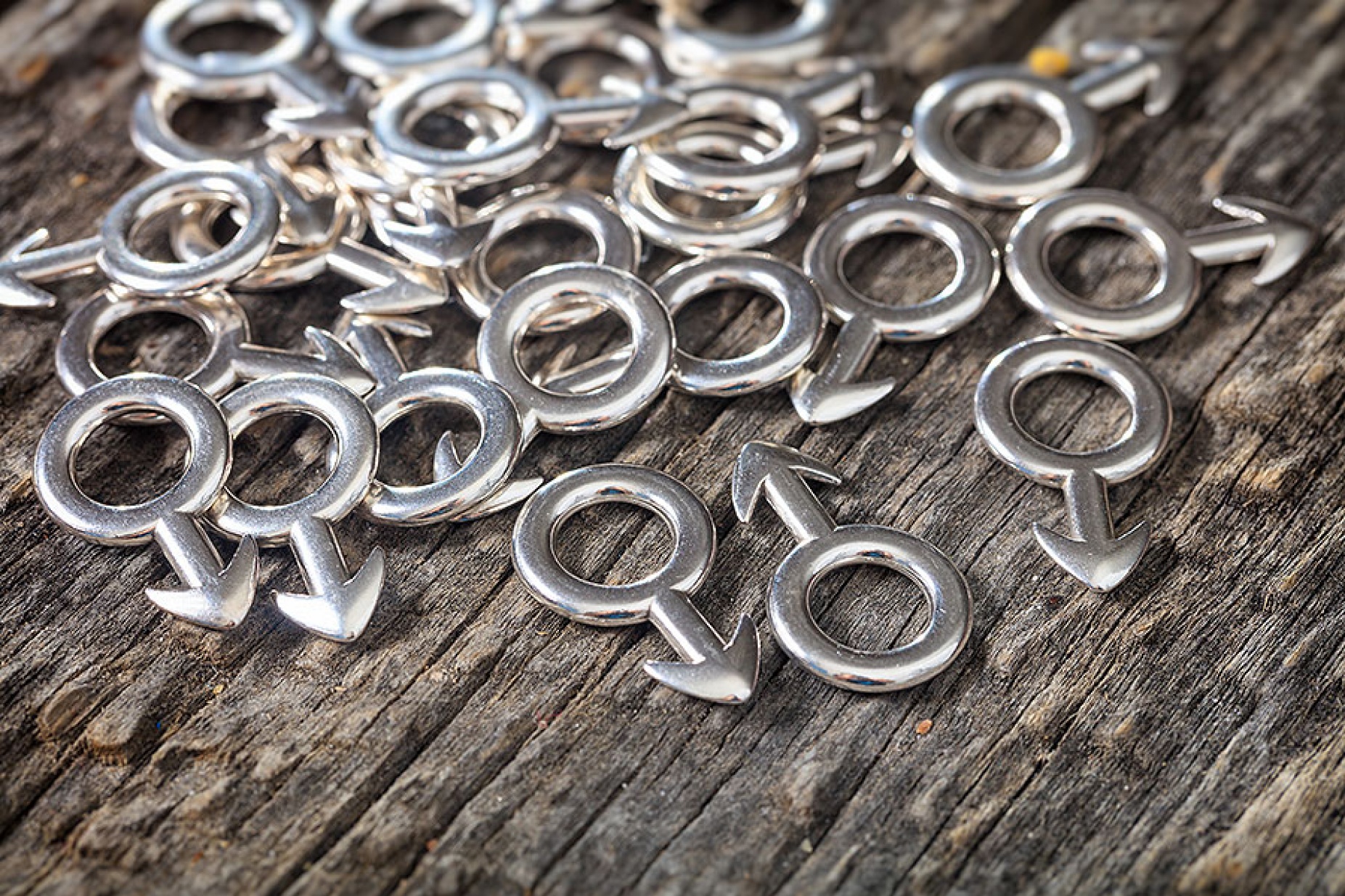 Closeup of metallic male symbols pile, on wooden background. 