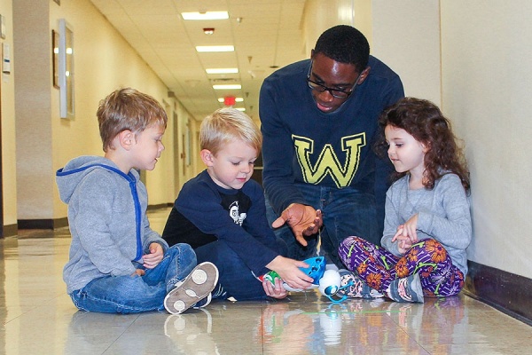 Zoom image: Tyler Eggleston (center) examines the Code-a-pillar with ECRC teacher Stanley Diih and classmates Christopher Coolidge and Ashley Blane. Photo: Keely Benson 