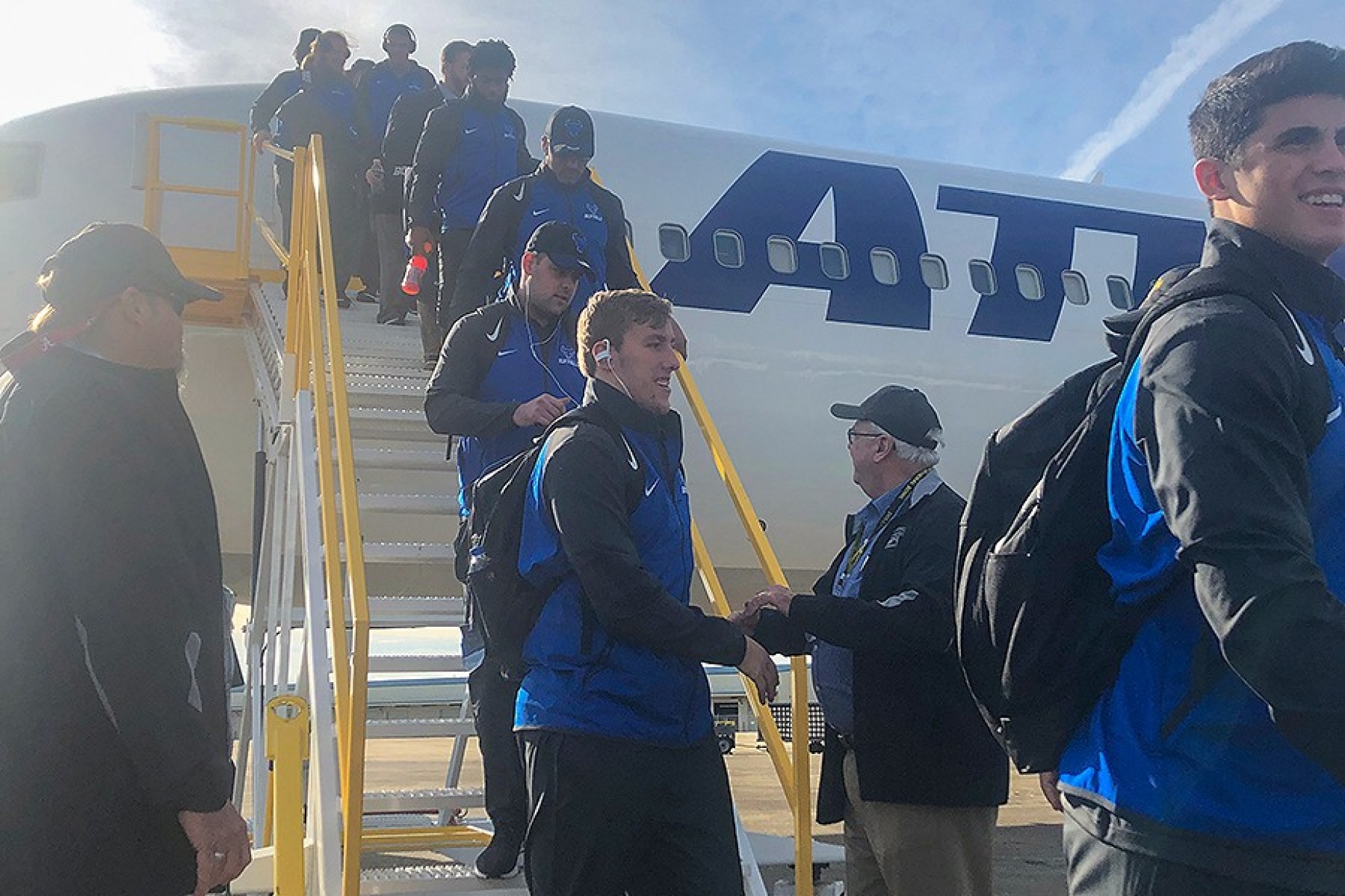 Photo of members of the UB football team getting off the plane in Mobile, Alabama. 