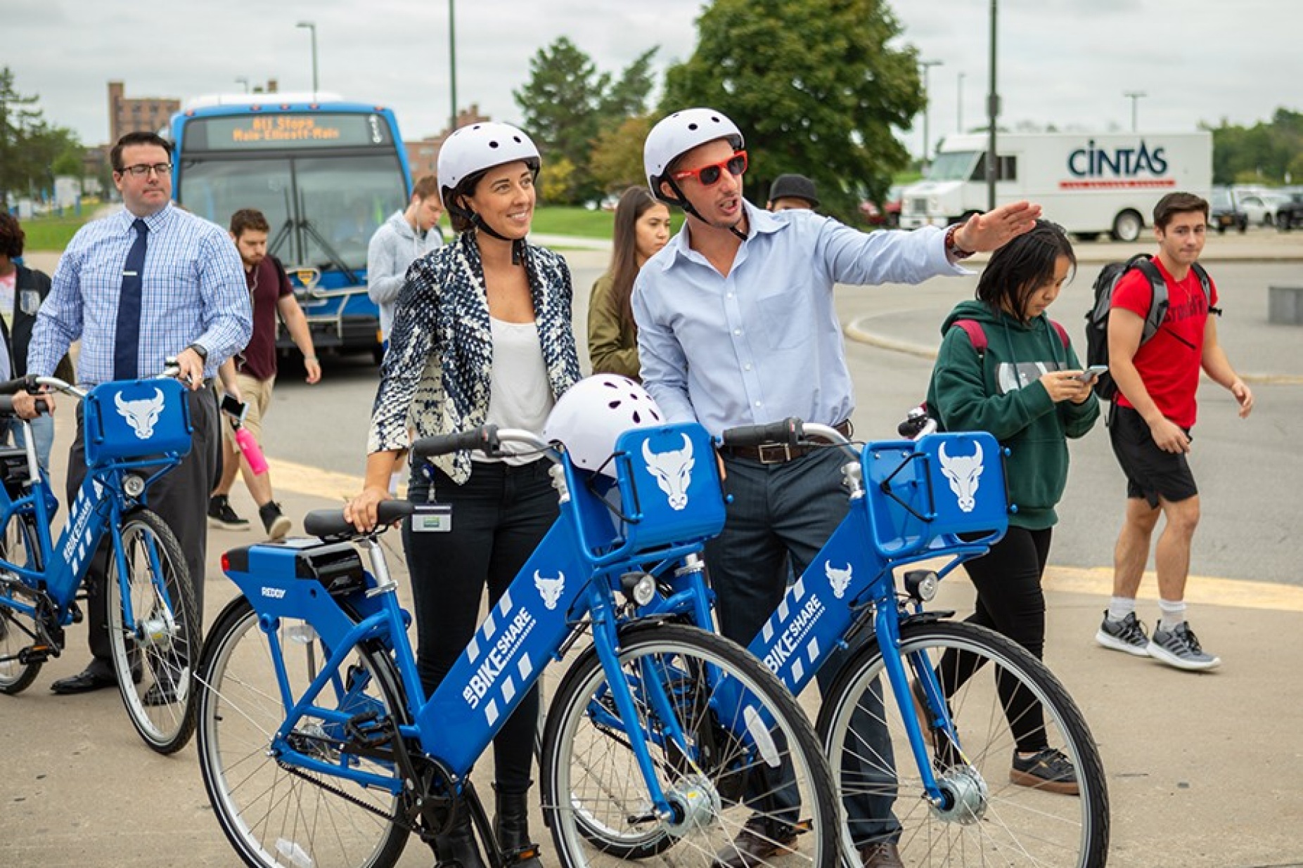 Woman and man wearing bike helmets talk before riding bikes. 