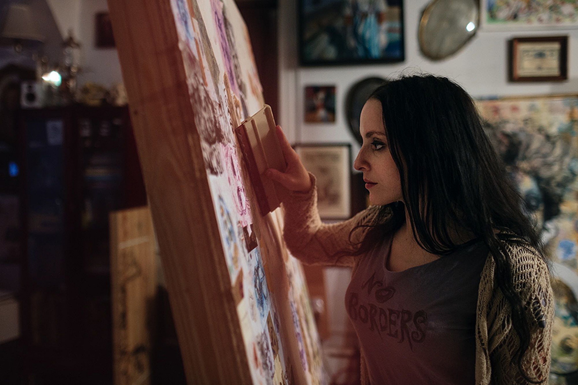 sideview of Molly Crabapple working on a painting. 