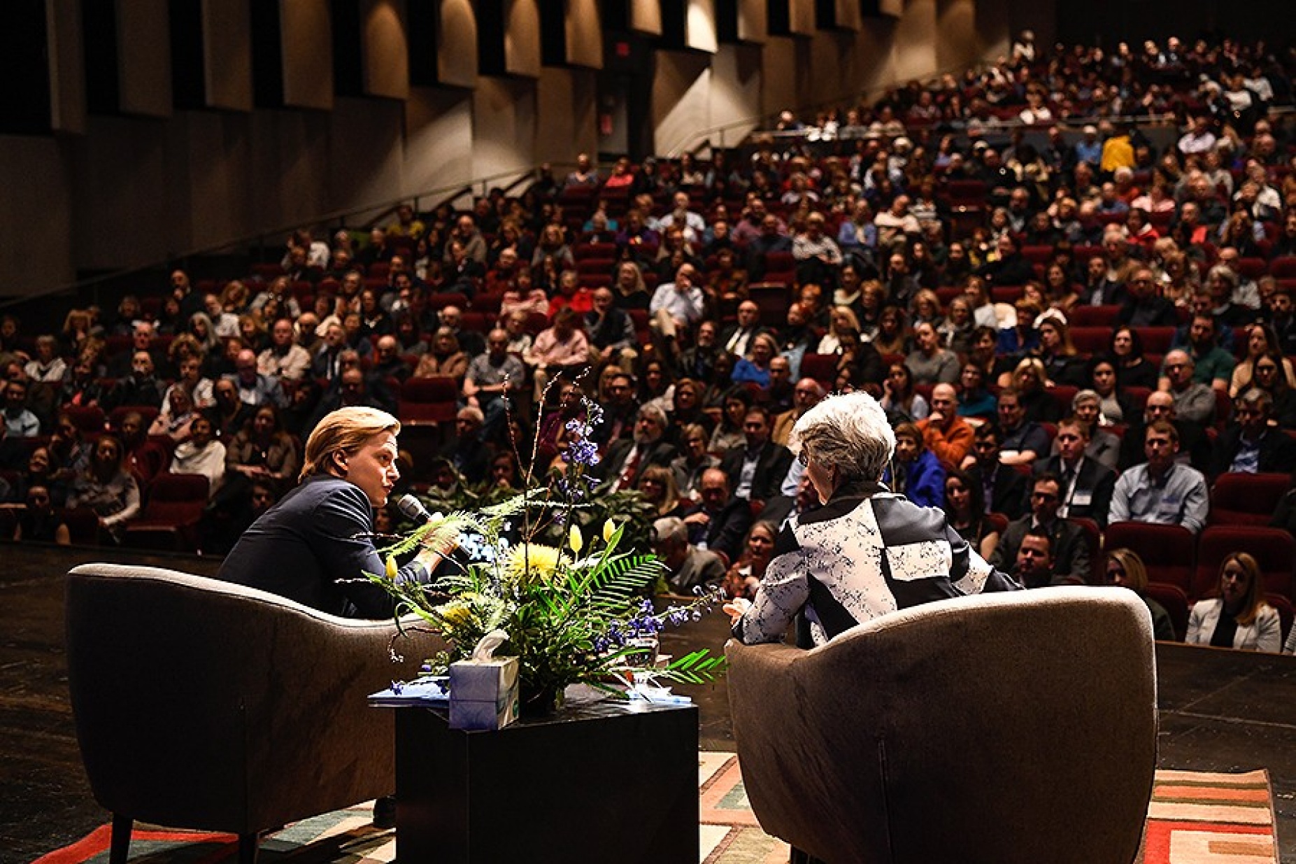 view from back of the stage with Ronan Farrow and Cristanne Miller in the foreground and a packed theater in the rear. 