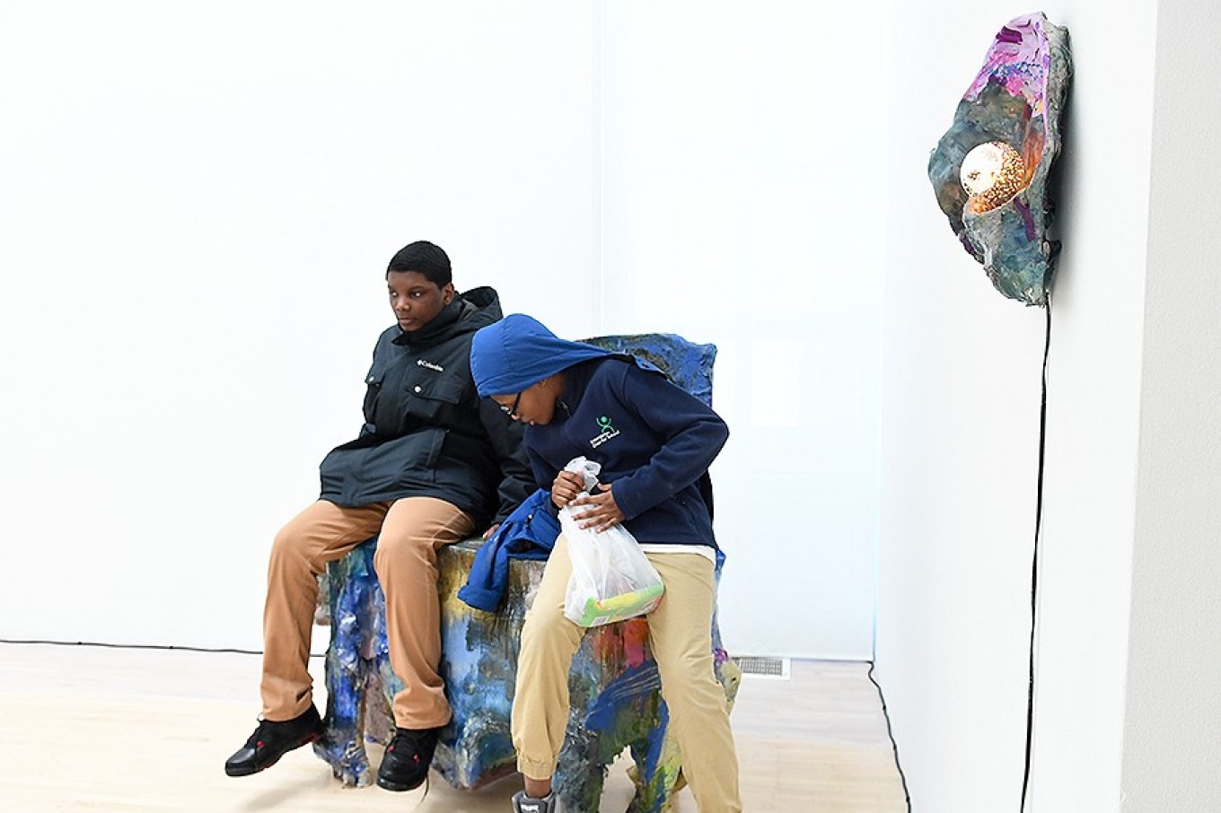 Clinton Peyton and Douglas Peay, visiting the UB Art Gallery, sit on a sculpture by artist Jillian Meyer that invites guests to sit on it. 