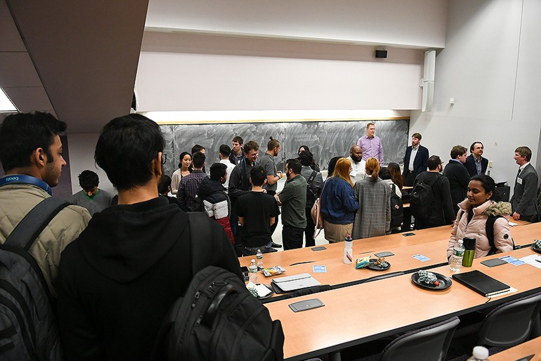 Students crowd to the front of the lecture hall to network with business leaders. 