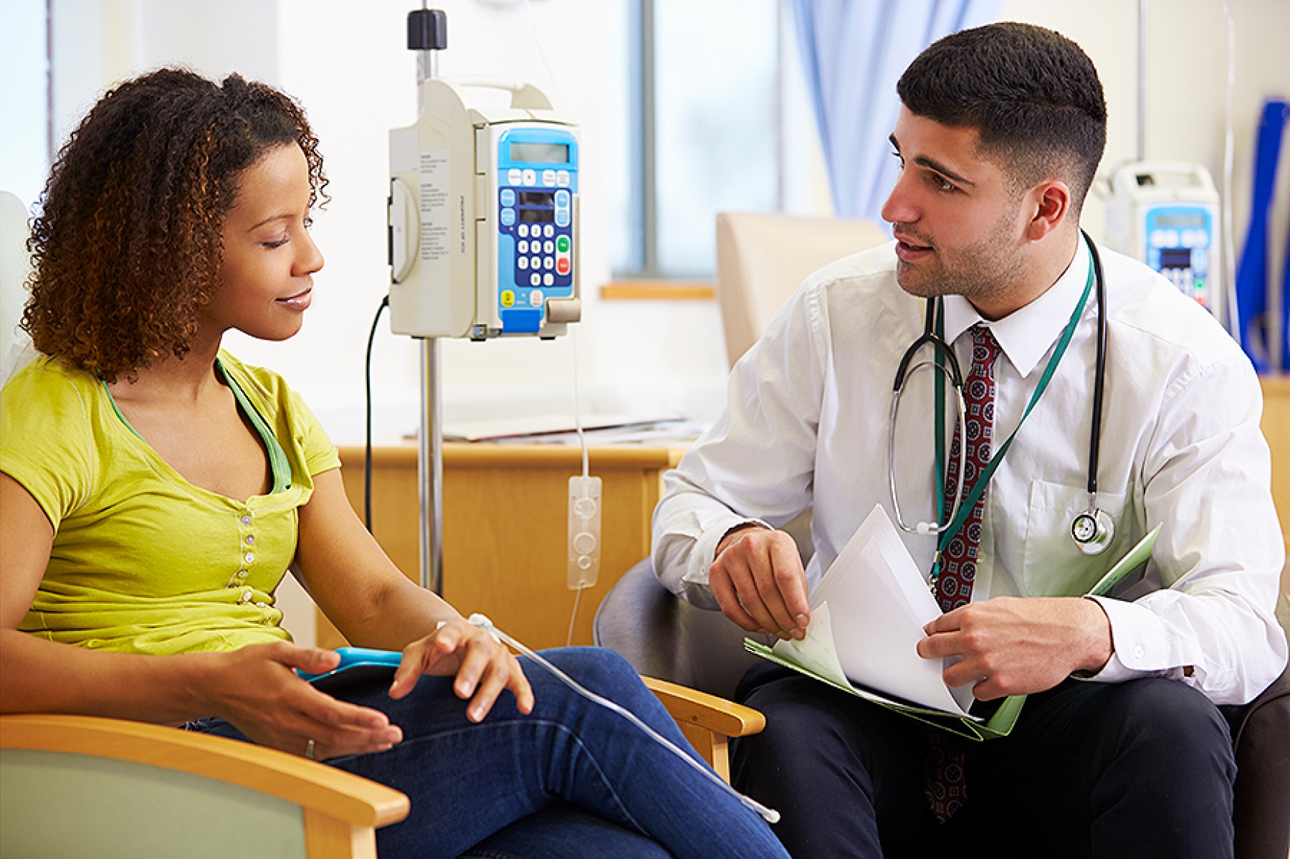 woman receiving chemotherapy, a doctor sits by her side. 