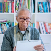 Older man looking at a tablet in a library. 