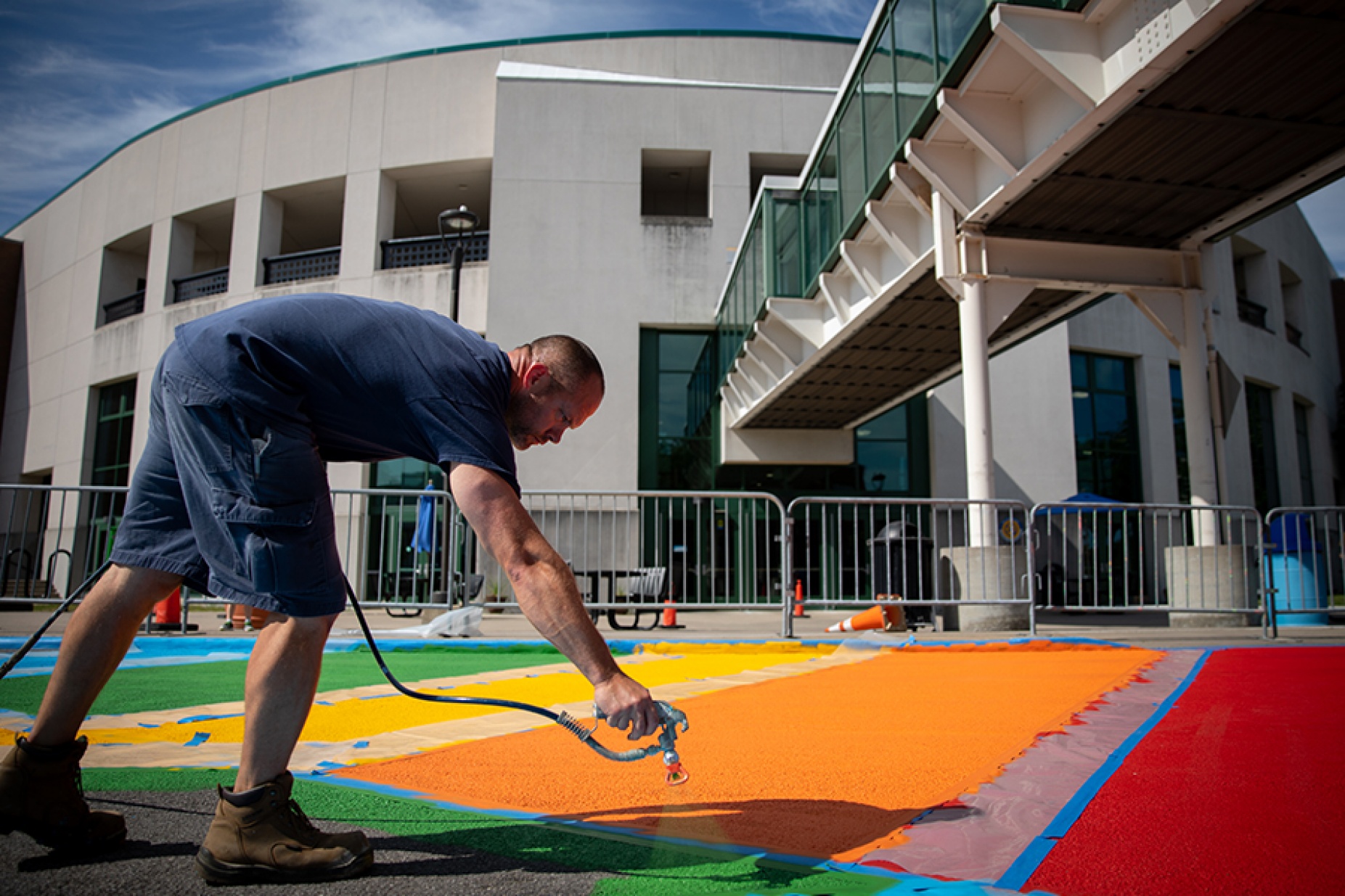 Facilities staff member Ryan Helfrey spray-paints the rainbow crosswalk across Putnam Way. 