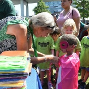 Theresa Quattrin helps a child put on a cape during a Summer STEM event at Canalside. 