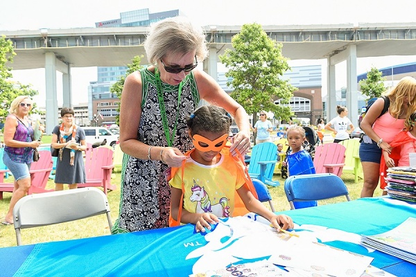 Zoom image: Teresa Quattrin helps "Research Ranger" Raven Thomas, age 6, don her cape. Photo: Nancy J. Parisi 