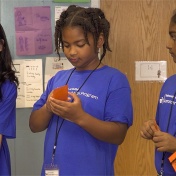 Young participants in the UB Summer Math Program smile as they work on an activity. 