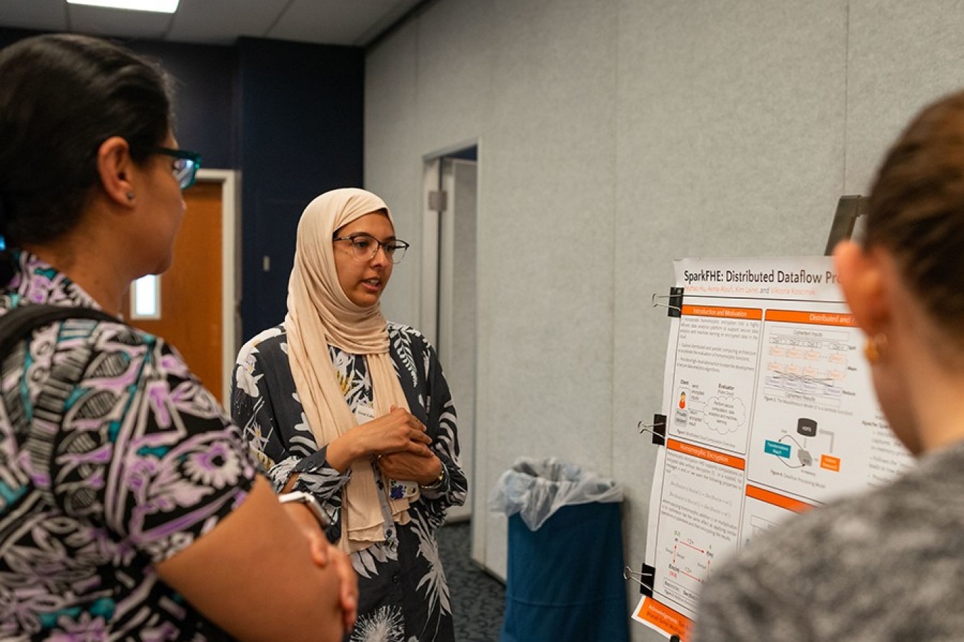 Three participants of Great Lakes Security Day gather around an academic poster. 