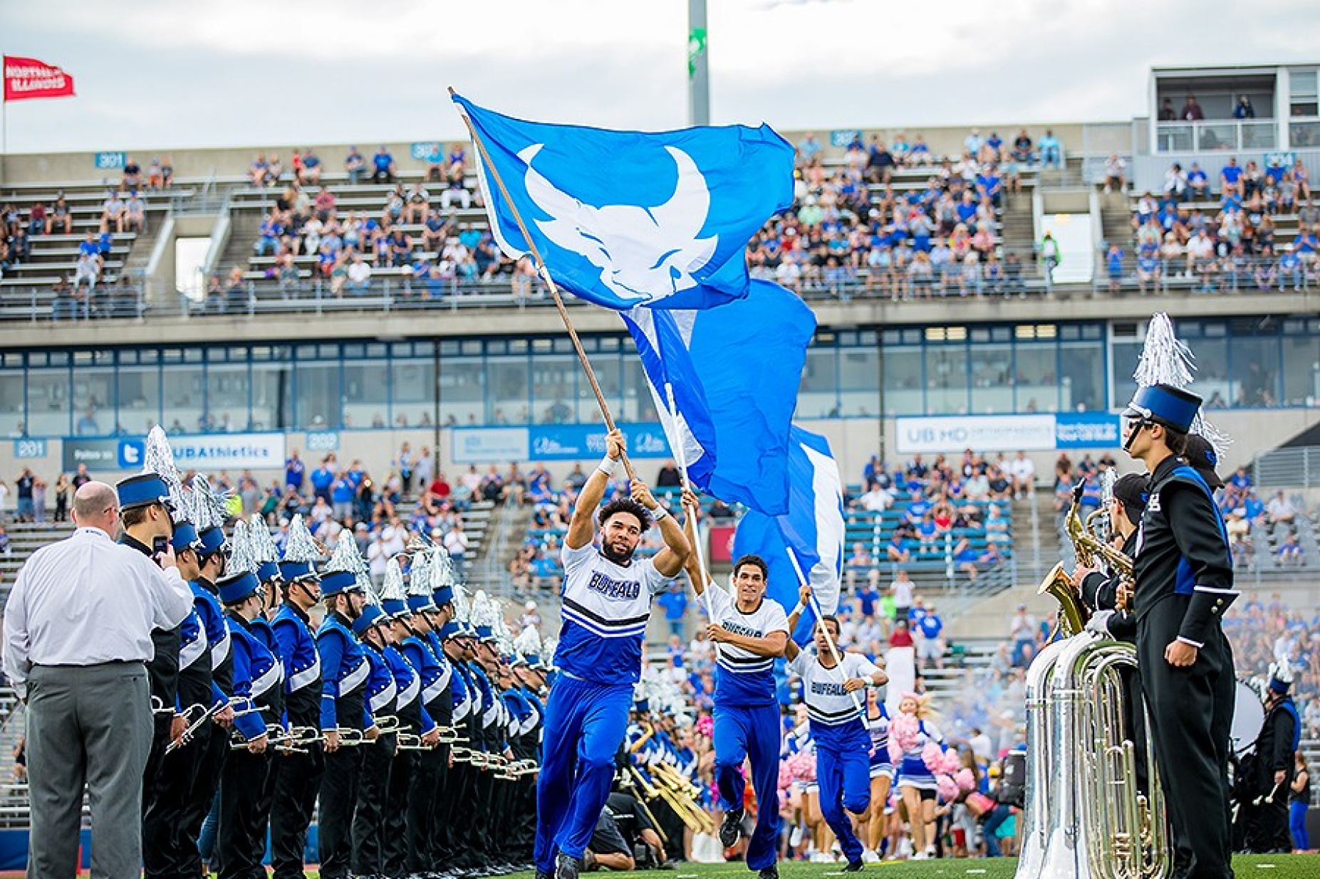 The cheer squad leads football players into the stadium. 