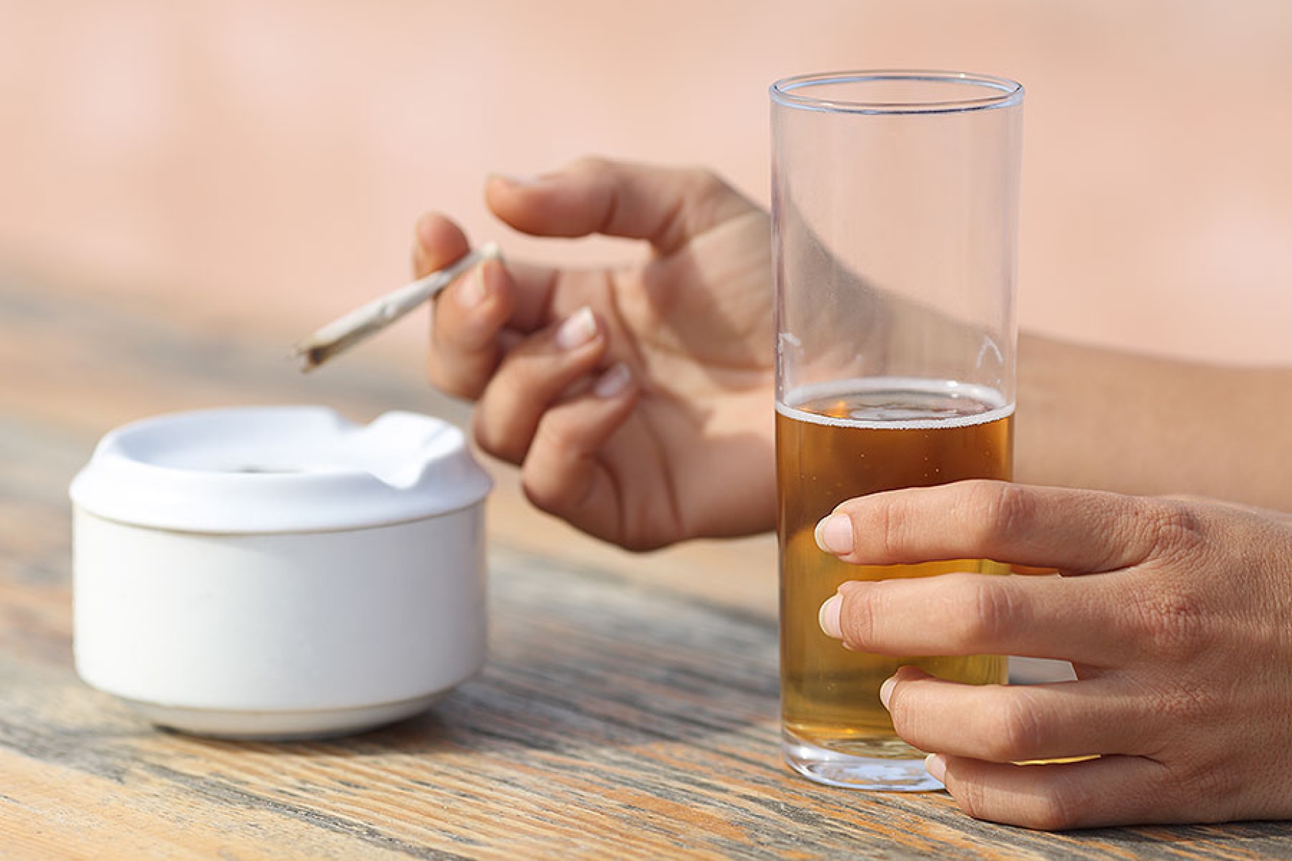 Close up of female hands holding a cigarette and a glass of beer. 