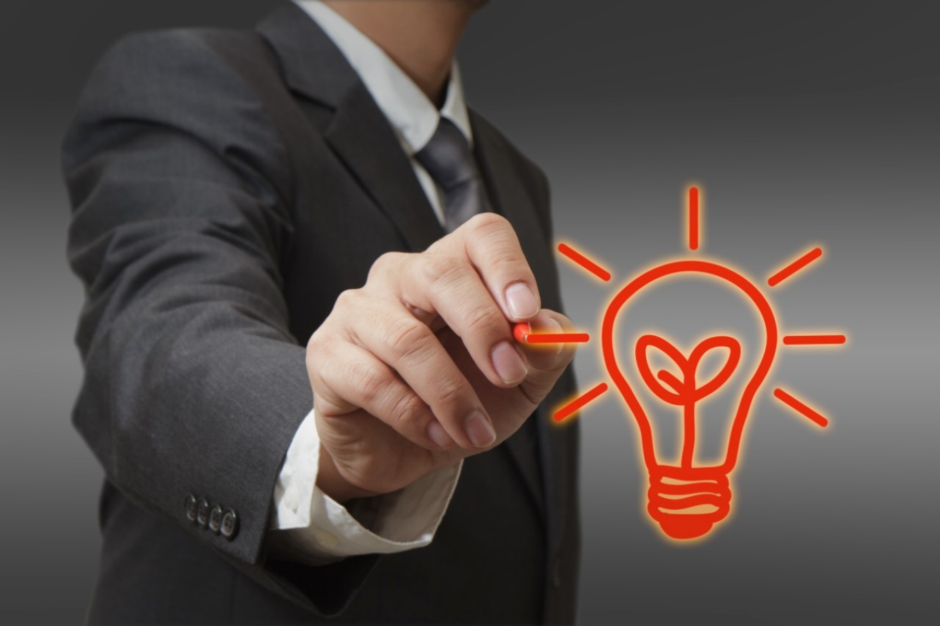 photo illustration of business innovation in which a man dressed in a business suit draws a light bulb. 