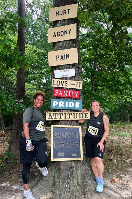 Zoom image: Stacy Tuberdyke (right) and a classmate pose together at the famous tree along the &quot;Yellow Brick Road,&quot; which is the final test of the National Academy’s fitness challenge. It is a grueling 6.1-mile course through a hilly, wooded trail built by the Marines. Photo: Courtesy of Stacy Tuberdyke 
