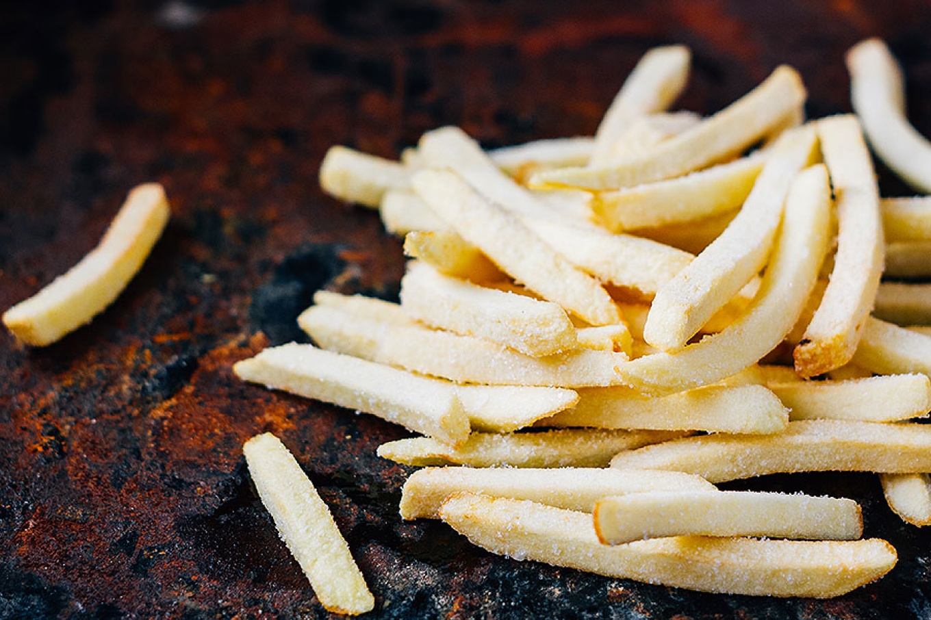 Frozen potatoes fry on a cast iron background. 