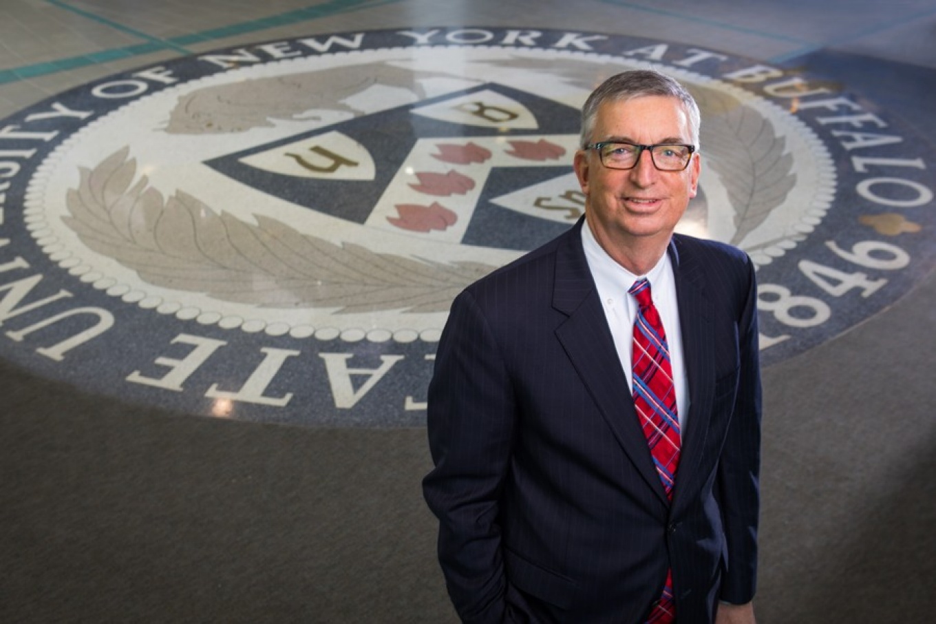 Scott Weber standing on the UB seal in the Student Union lobby. 