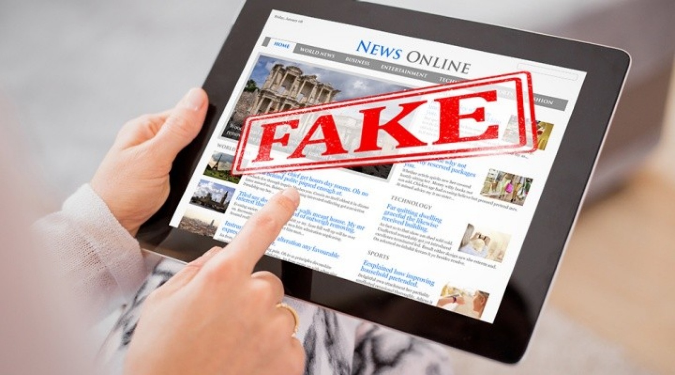 News story on a tablet, with the word "FAKE" emblazoned on the story. 