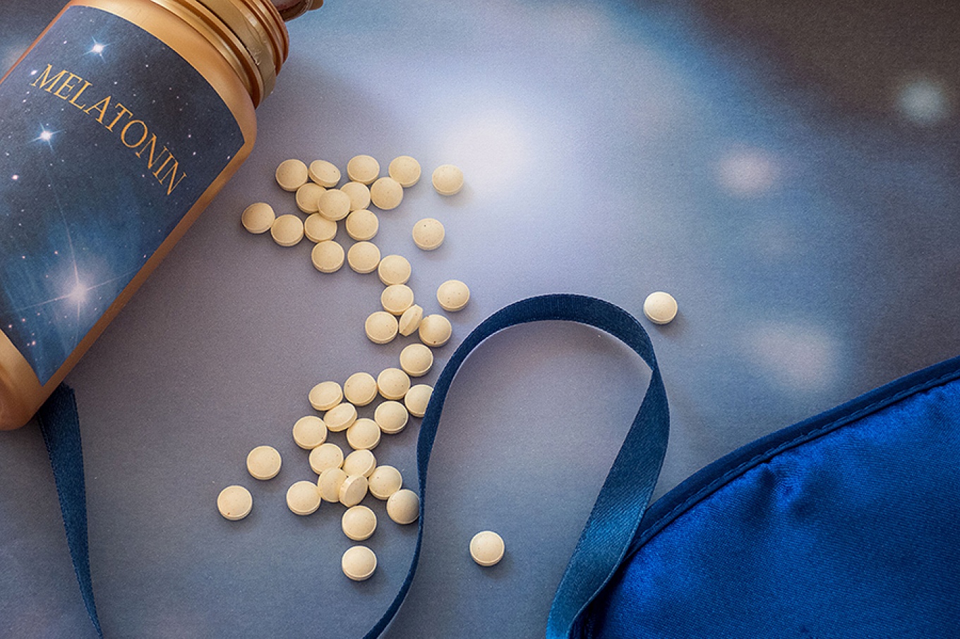 Bottle that reads, "Melatonin", pills and a sleep mask. 