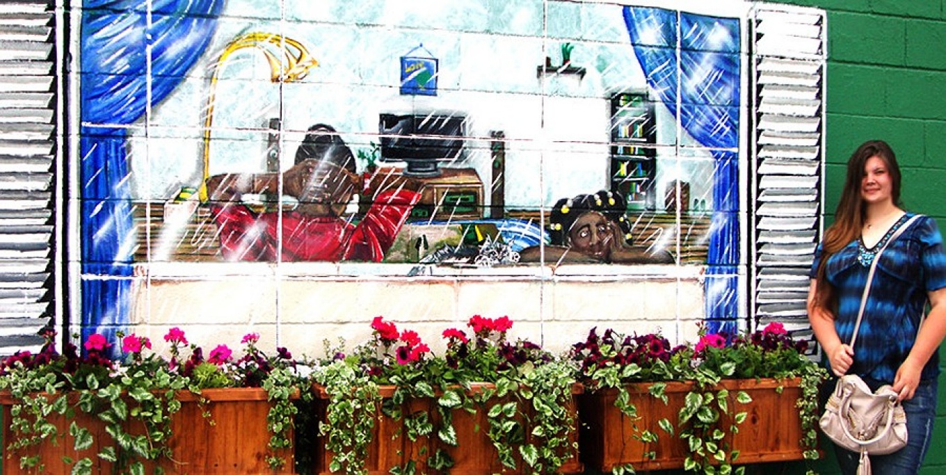 Amanda Hart standing next to a mural on an exterior wall of the Matt Urban Hope Center.