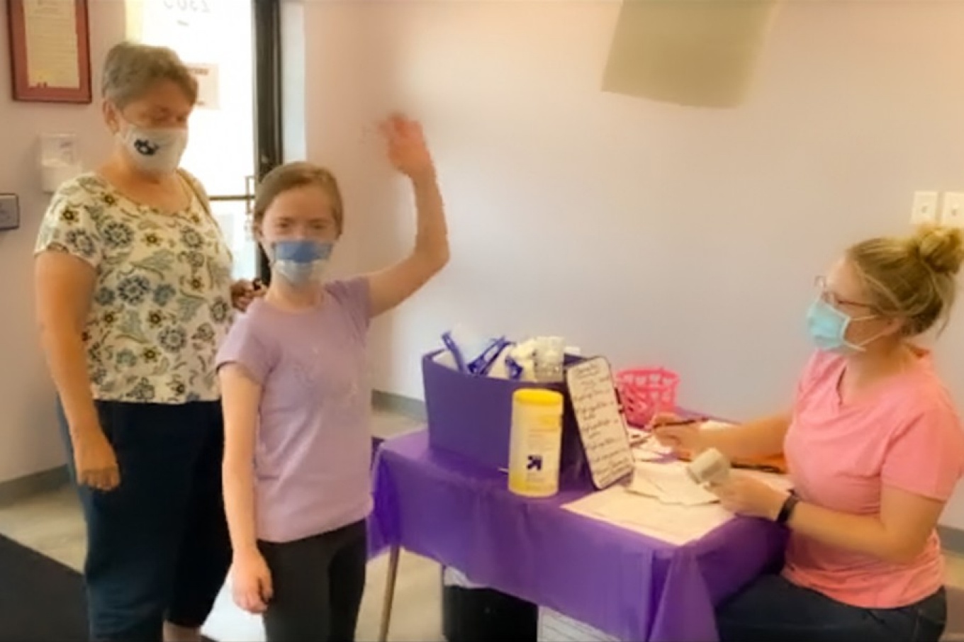 A young student waves as a health check is completed by nursing student Hannah Bogart. 