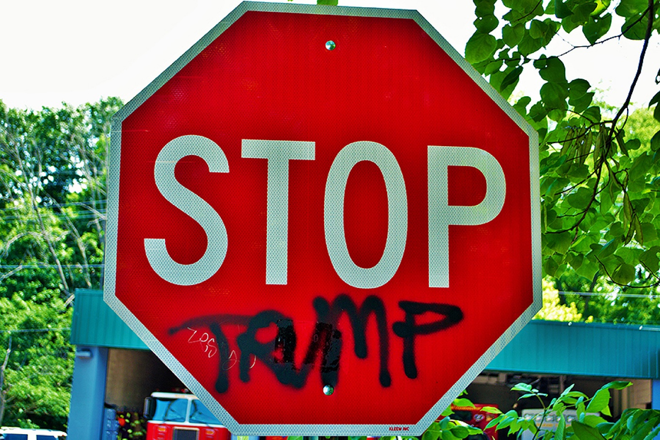 A stop sign with the name "Trump" spray painted below the word "stop.". 