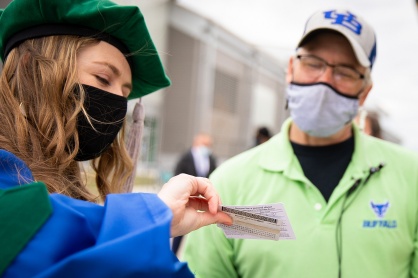 Zoom image: Tim Belzile (right), a special events staff member, checks the vaccine card of a graduate attending the Jacobs School commencement. Students and guests had to show proof of a negative COVID-19 test or vaccination. 