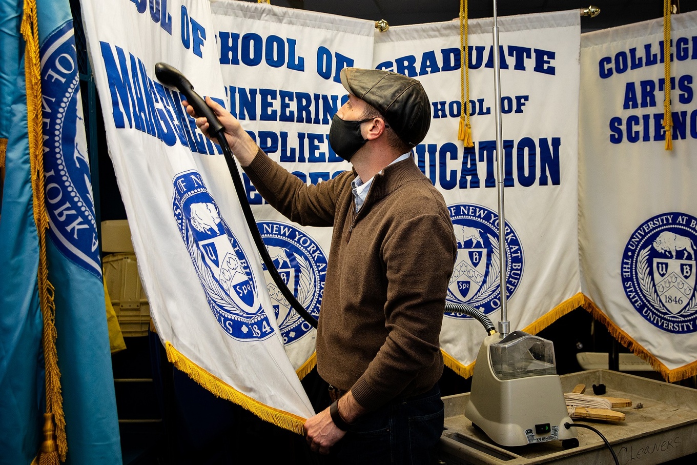 Zoom image: Doug Borsuk, ogistics manager with Event Planning and Services, steams banners in a locker room of UB Stadium for several of the school commencement ceremonies. 