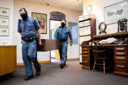 Zoom image: Two University Police officers pick up the University Mace from the University Archives ahead of Commencement Weekend. The Mace is used at seven of the commencement ceremonies held throughout the weekend. 
