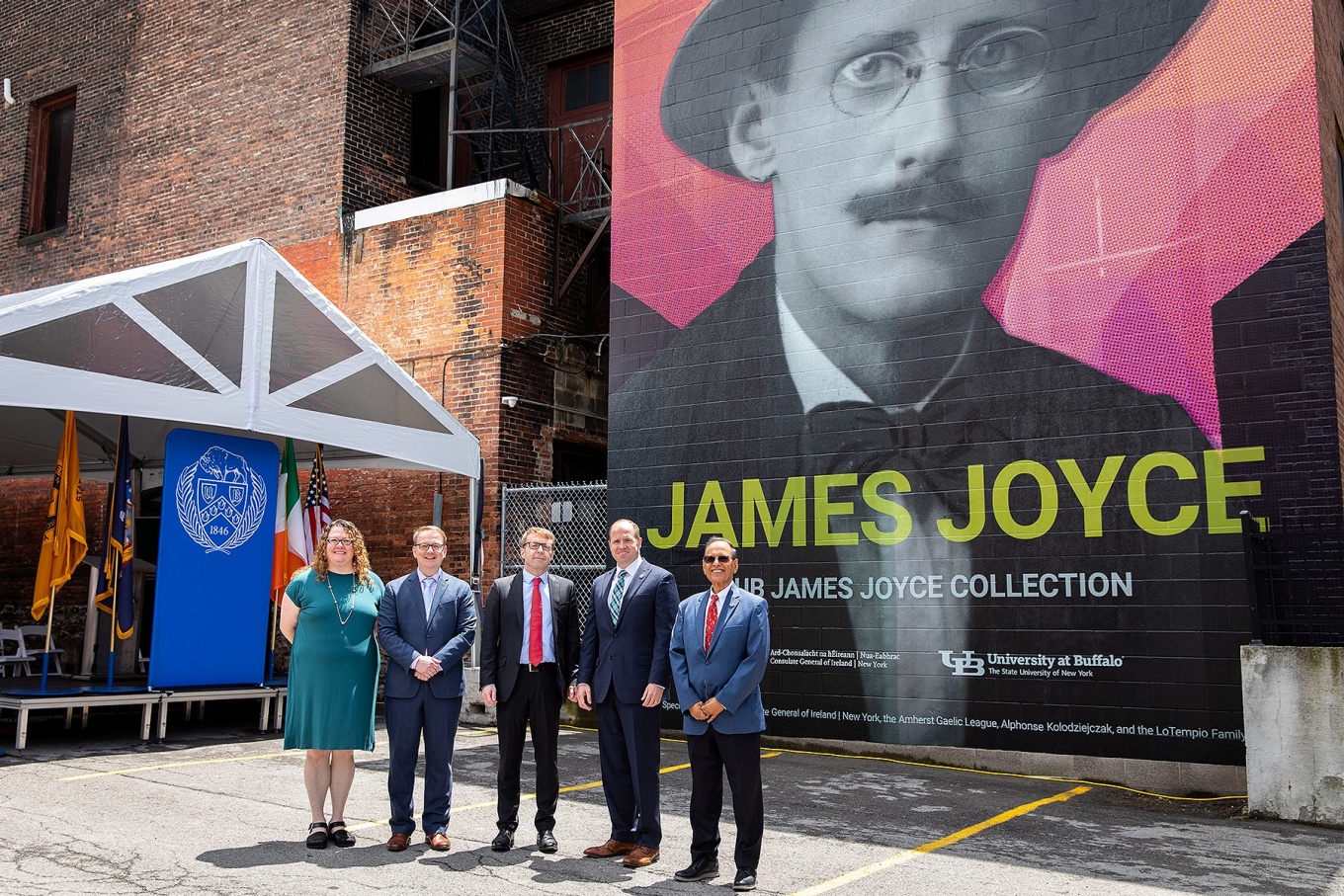 Zoom image: From left: Evviva Weinraub Lajoie, James Maynard, Ciarán Madden, Tim Kennedy and Satish K. Tripathi stand together in front of the new James Joyce mural. Photos: Meredith Forrest Kulwicki 