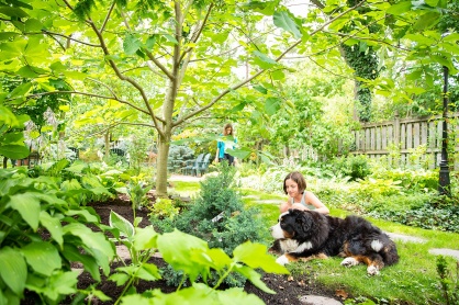 Zoom image: A young visitor stops to give Sophie a pet while her family explores the garden. 