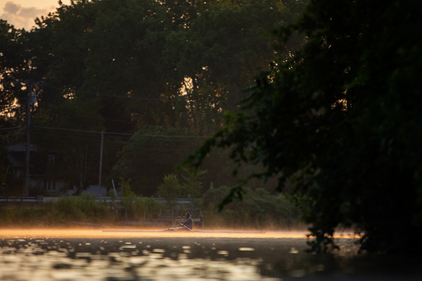 Zoom image: The morning sunrise illuminates the creek water, making a silhouette of Barnum. She often rows in the morning because the water is calmer. 