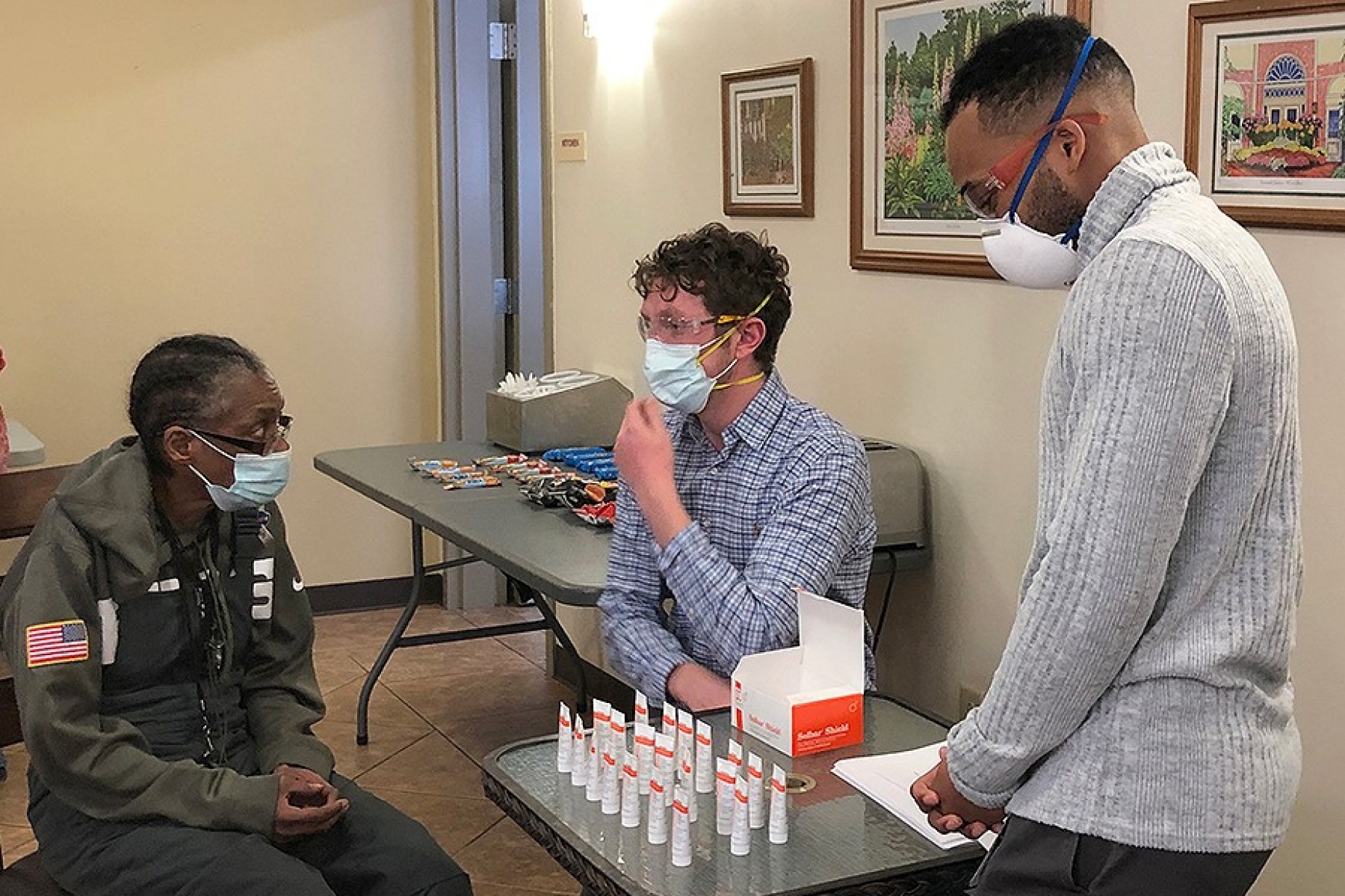 Medical students Isaac Swartzman, left, and Michael Augustin counsel a Hope Gardens resident on the proper use of sunscreen. 