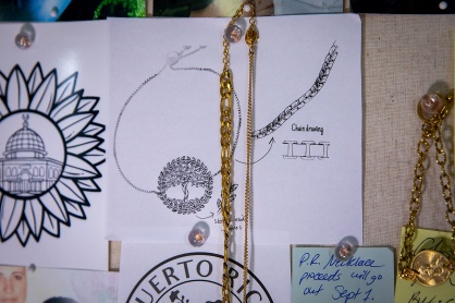 Zoom image: Above her workstation, Aref displays ideas for future creations. Featured here is the rough draft for a bracelet she calls “Arina - Mother Tree of Life.” She says the inspiration for this piece is, “If you take care of the mother tree of life, she will take care of you.” The piece is currently in production and will be available later this summer. 