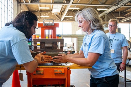 Zoom image: Participants operate a mechanical block press machine to make earth bricks. Photo: Meredith Forrest Kulwicki 