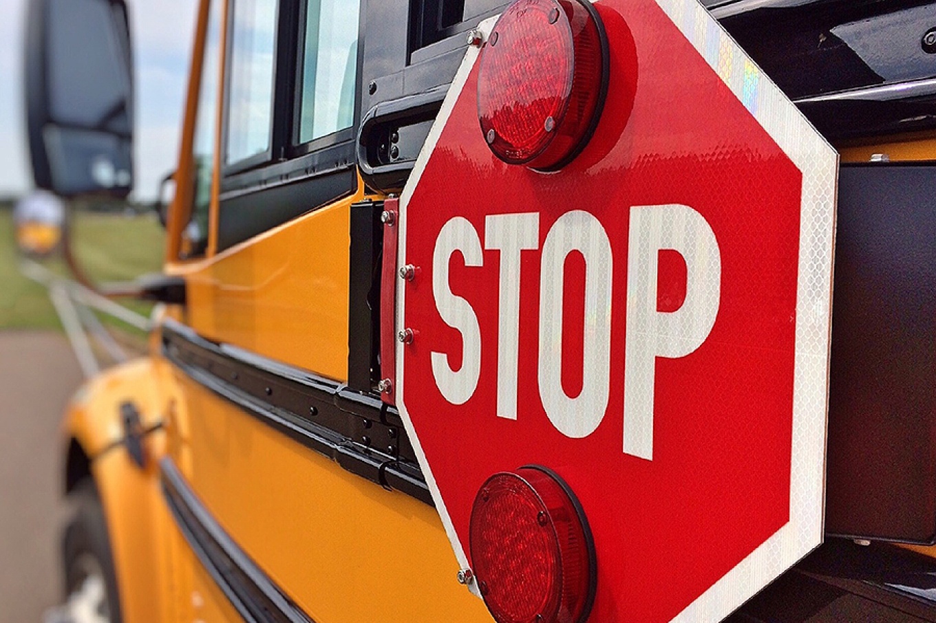 Close up view of a school bus with the stop sign featured on the side. 