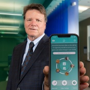 Ralph Benedict holds a smartphone with his conscientiousness app on the screen. 