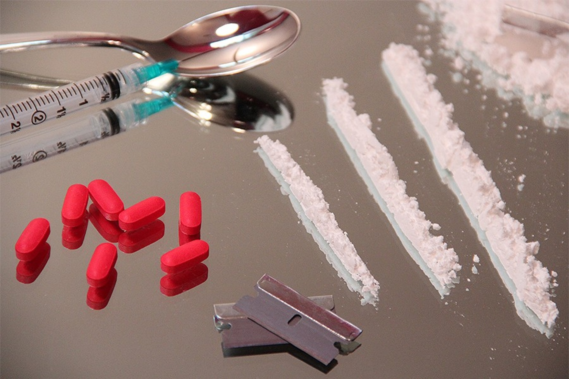 A variety of illicit drugs including pills and white powder and equipment such as syringes, a spoon and razor blades. 