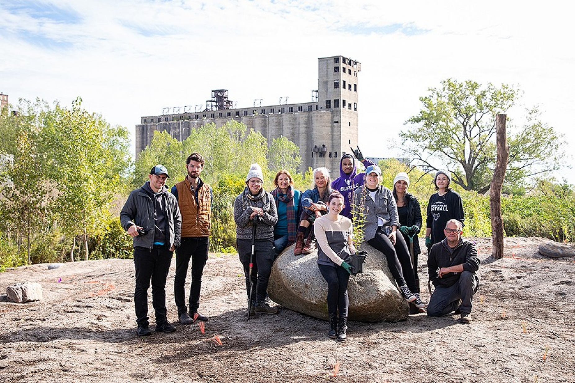 Dara Friedman (seated on the rock in the center of the group) and her students pictured together at the site of the labyrinth at Silo City. 