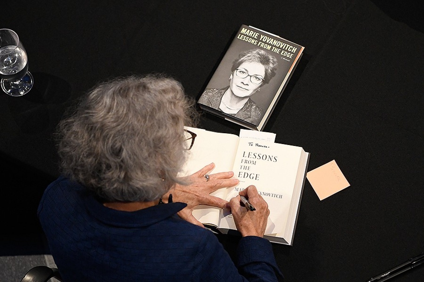 View from above as Marie Yovanovitch signs a book. 