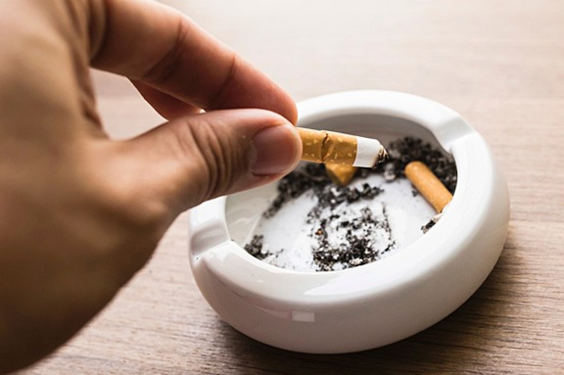 putting a cigarette out in an ashtray. 