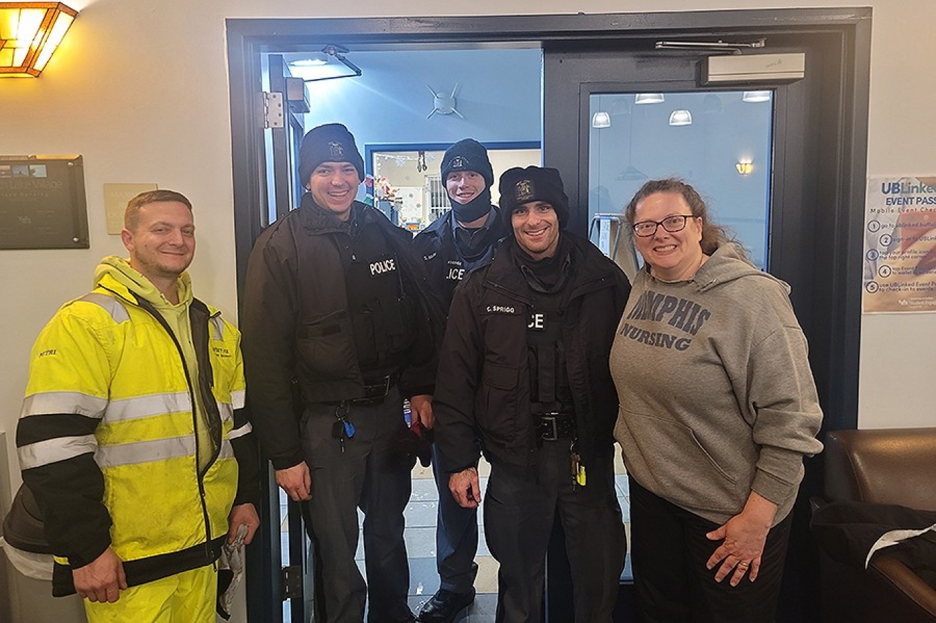 Zoom image: A group effort: (from left) Carl Mitri, a high-lift driver from Facilities, and UPD Officers Luke Galmarini, Jay Lawrence and Chris Sprigg pose with one of the motorists they rescued during the storm. Photo: University Police 