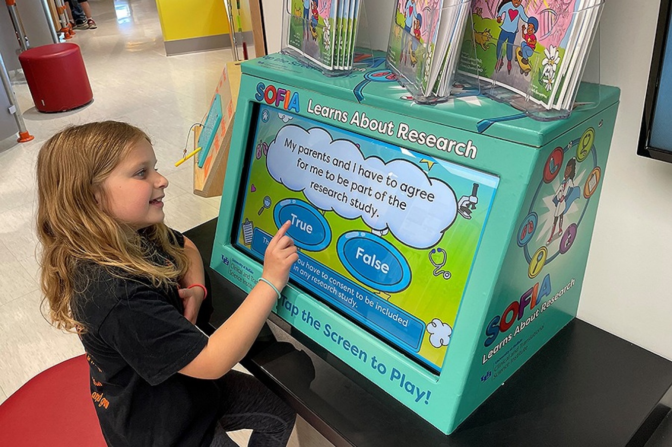 A child plays a game on a touchscreen computer display. 
