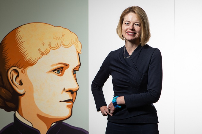 Kelly Hayes McAlonie poses next to an image of Louise Bethune. 