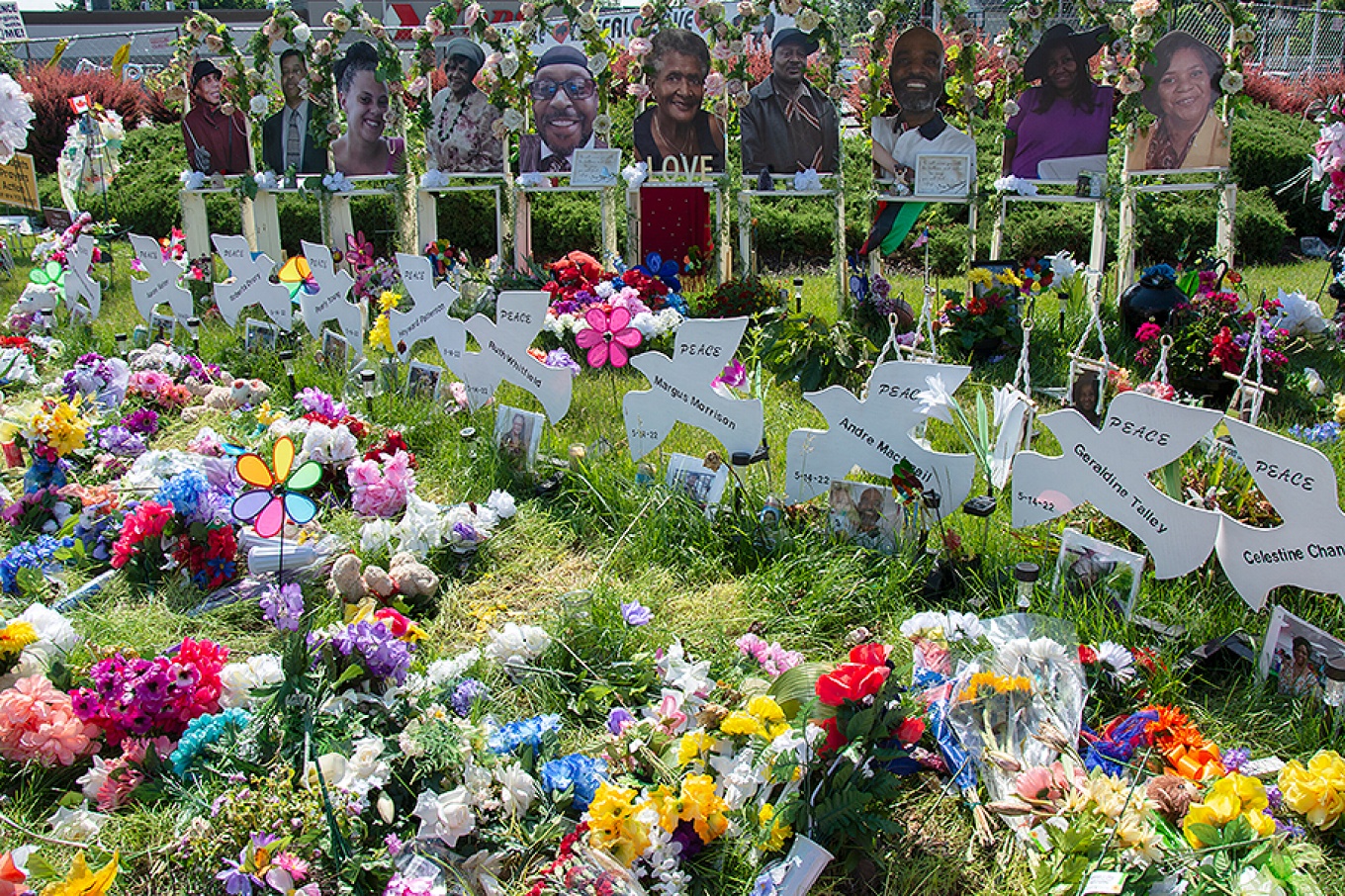 flowers and peace dove signs at memorial to victims of Tops mass shooting. 