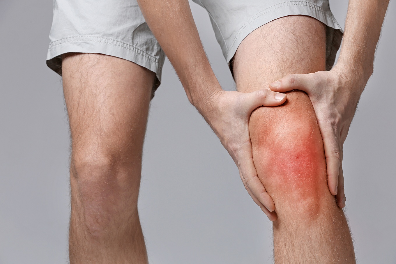 Person grabbing their inflamed knee. 