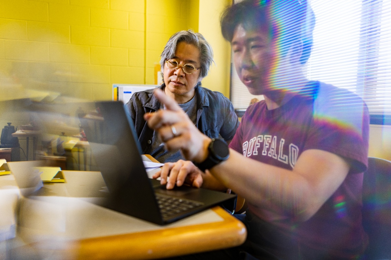 Jong Han works with graduate student Xi Chen in his Fronczak Hall office. 