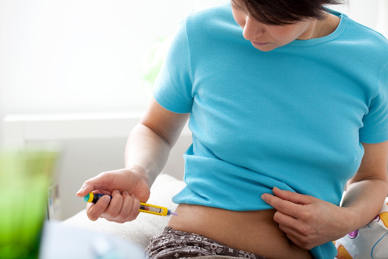 A woman uses an insulin pen to give herself an injection. 