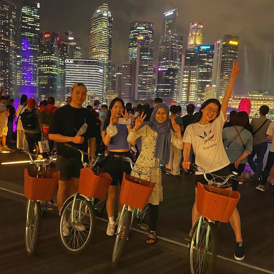 Four young adults on bikes with a large city in the background. 